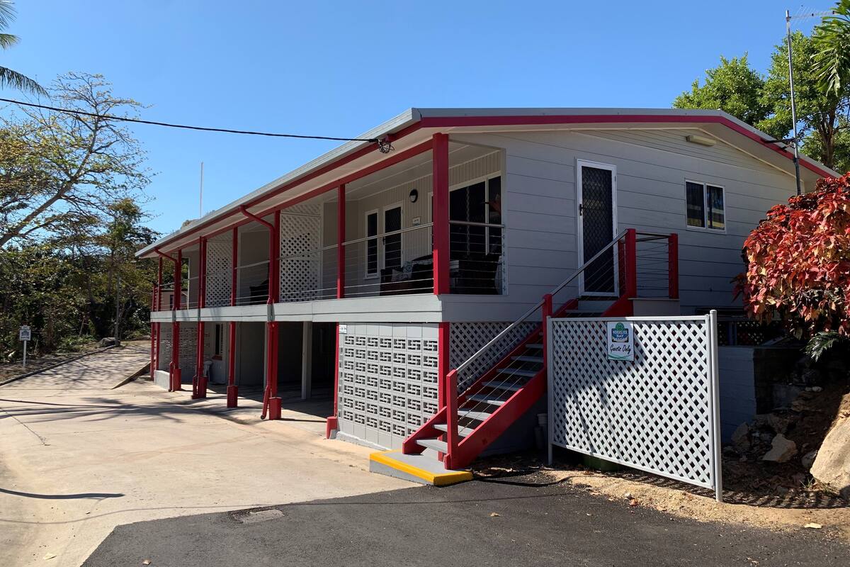 A two-story building with a red and white exterior, a covered porch, and a staircase leading to the upper floor.