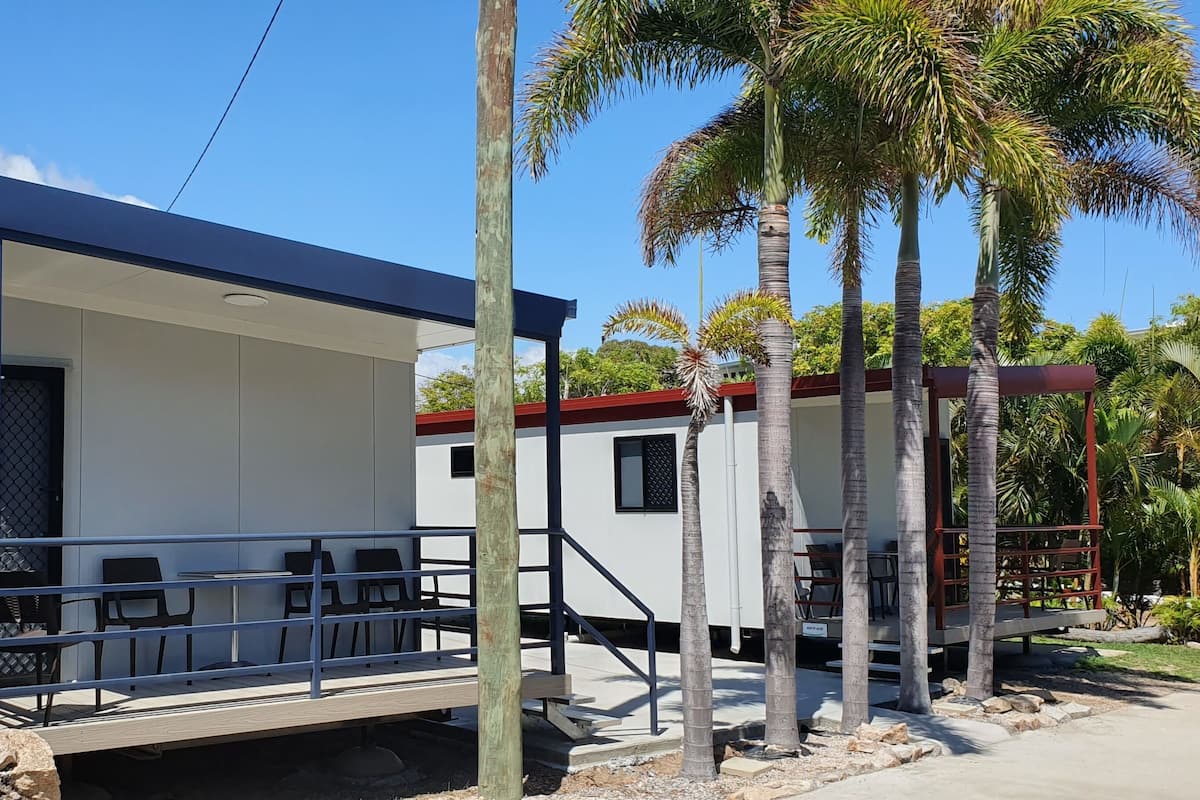 A modern, two-story building with a flat roof and a covered outdoor seating area.