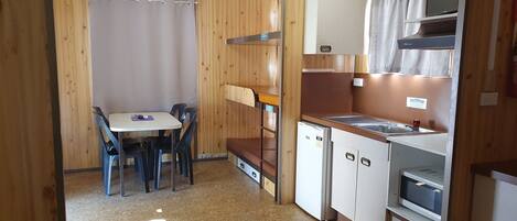 A compact kitchen with a table and chairs, a refrigerator, a microwave, and a sink.