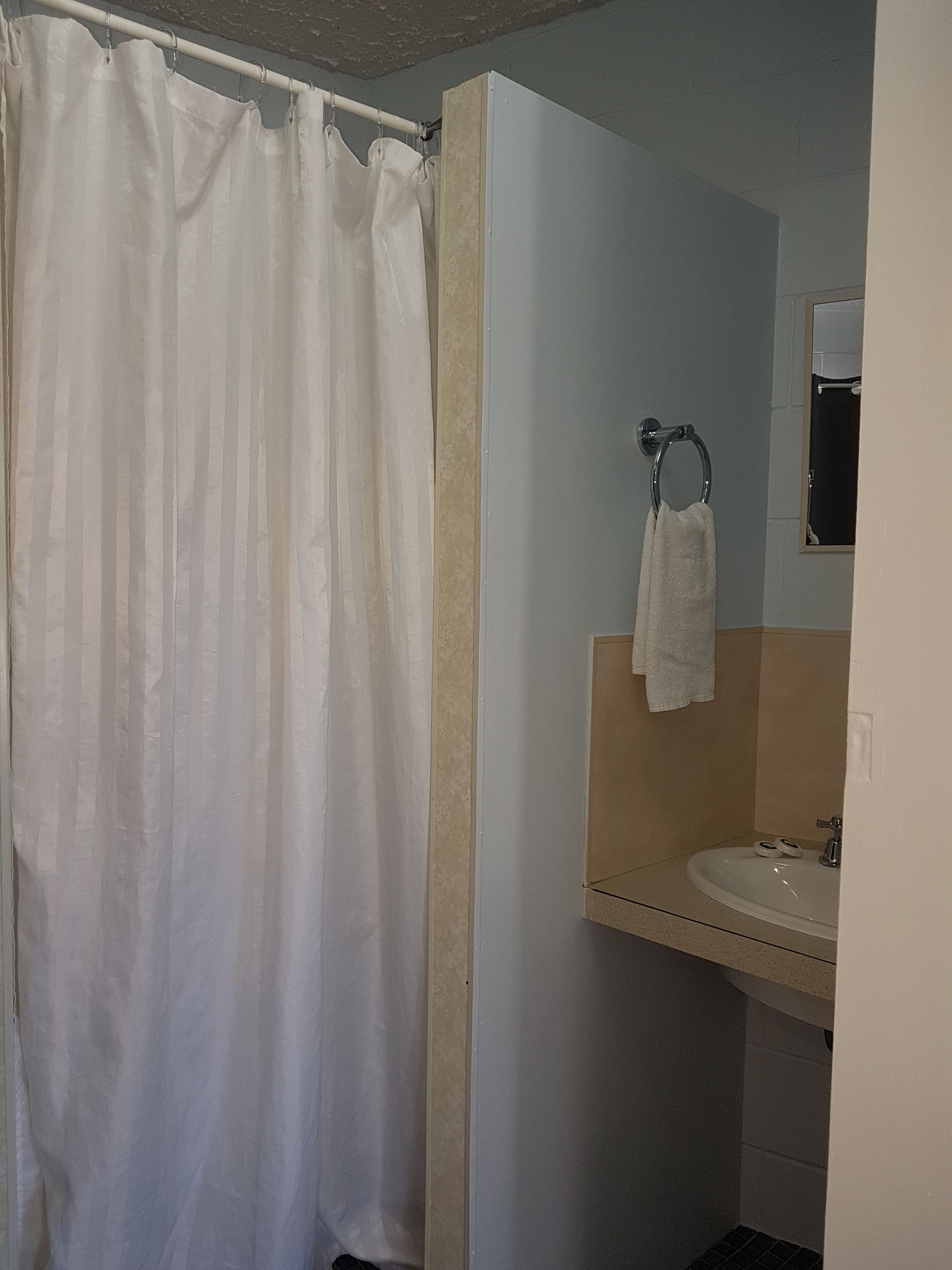 A bathroom with a shower curtain, a sink, and a towel hanging on the wall.