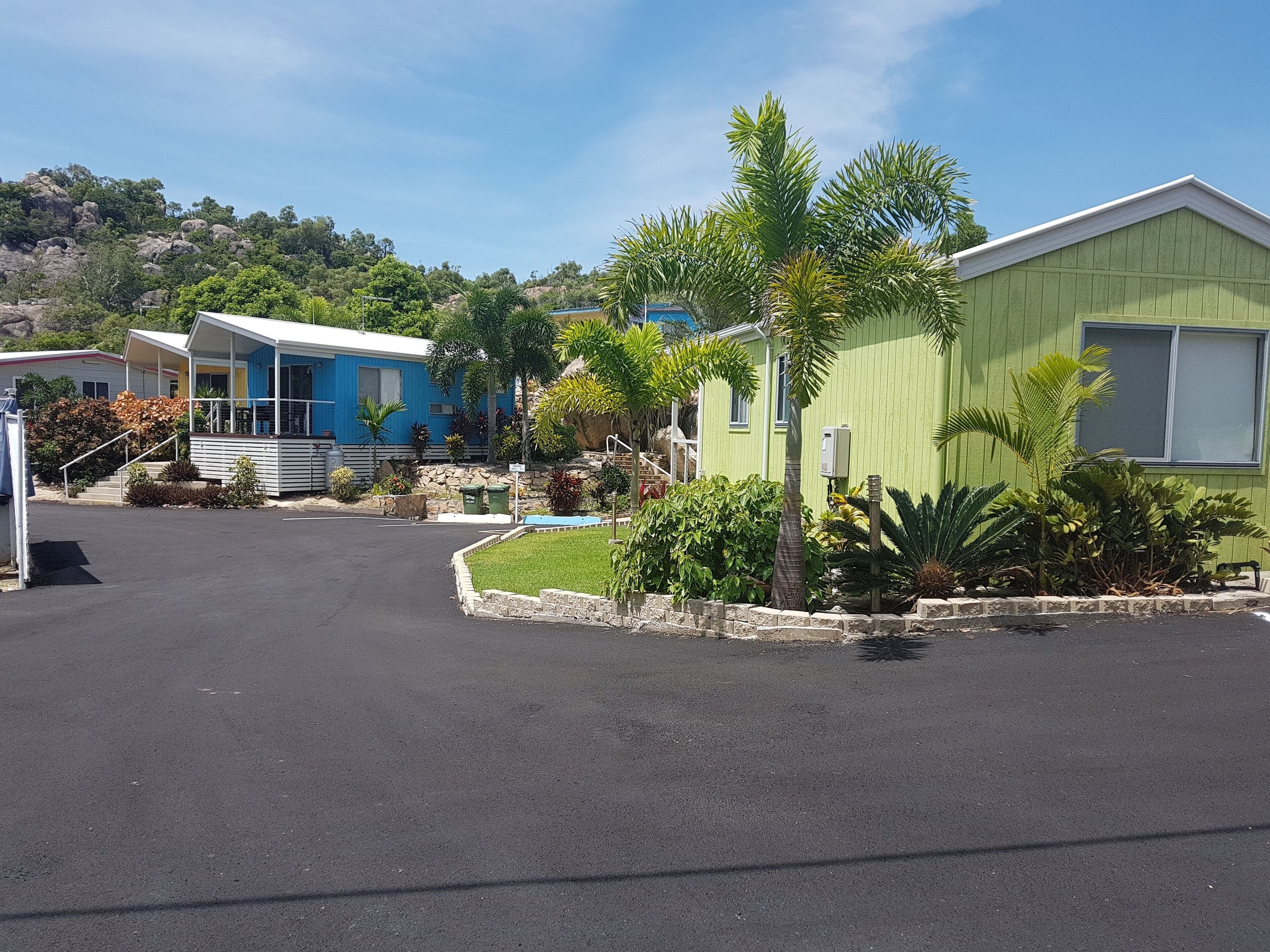 A row of mobile homes with a paved driveway and landscaped gardens.