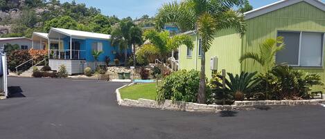 A row of mobile homes with a paved driveway and landscaped gardens.