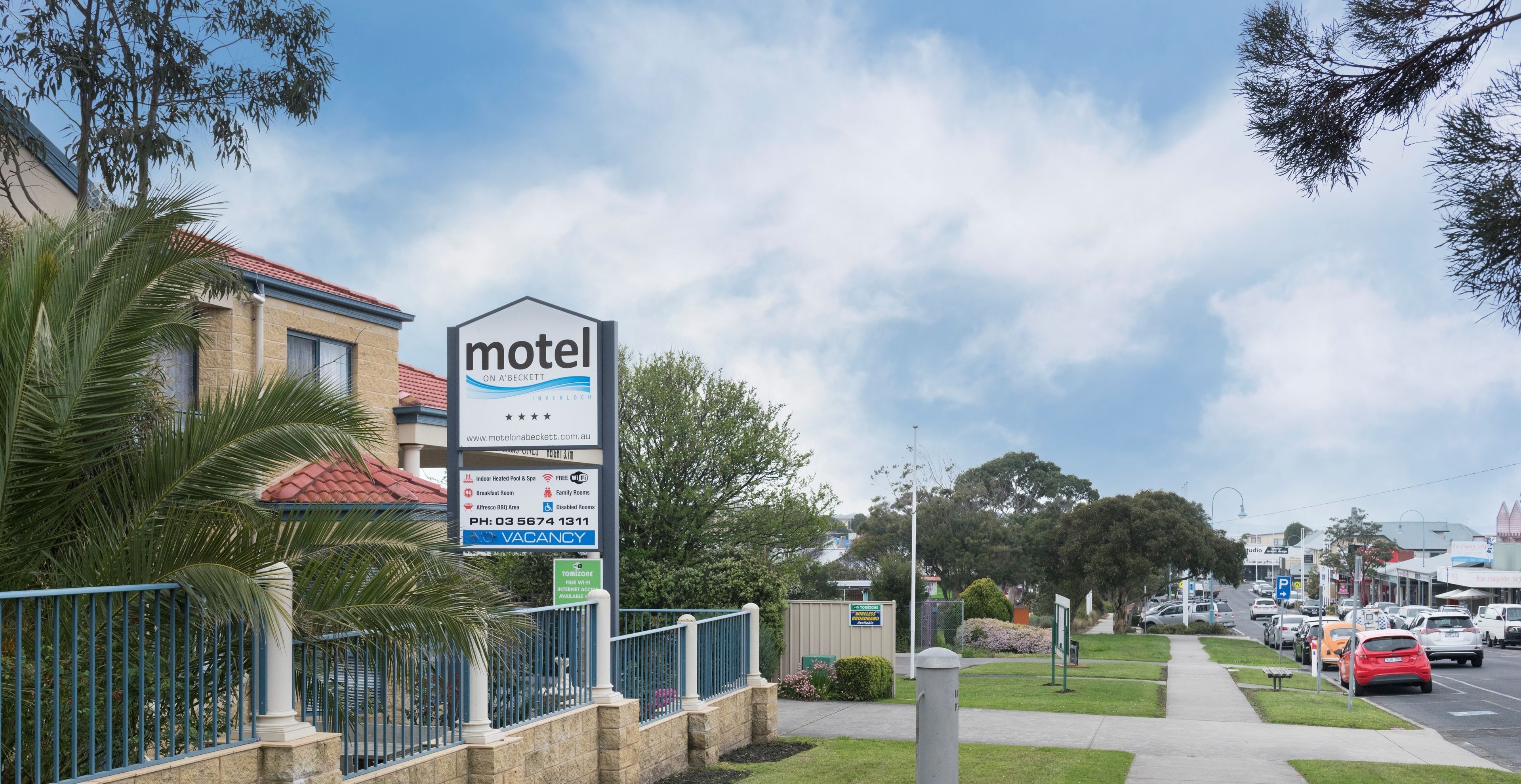 Motelbordes met faciliteiten vermeld, waaronder een overdekt zwembad, barbecueplaats, ontbijt, familiekamers en parkeergelegenheid.