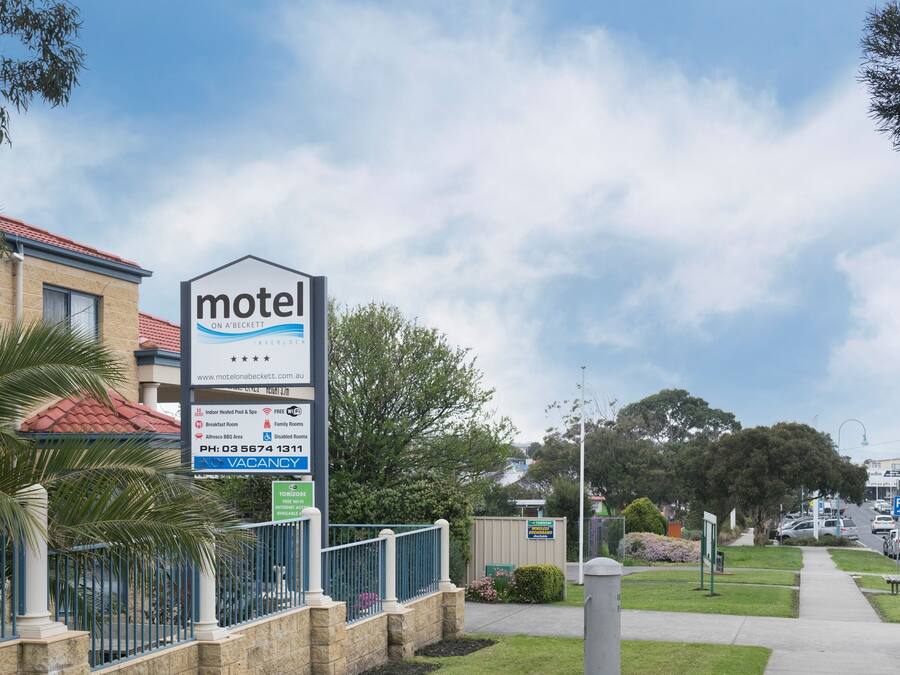 Señal de motel que enumera los servicios, incluyendo piscina cubierta, zona de barbacoa, desayuno, habitaciones familiares y estacionamiento.