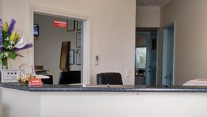 A reception desk with a 'Welcome On A'Beckett' sign, a 'motel' sign, and a 'Warning' sign in the background. - Motel on A'beckett (Inverloch)