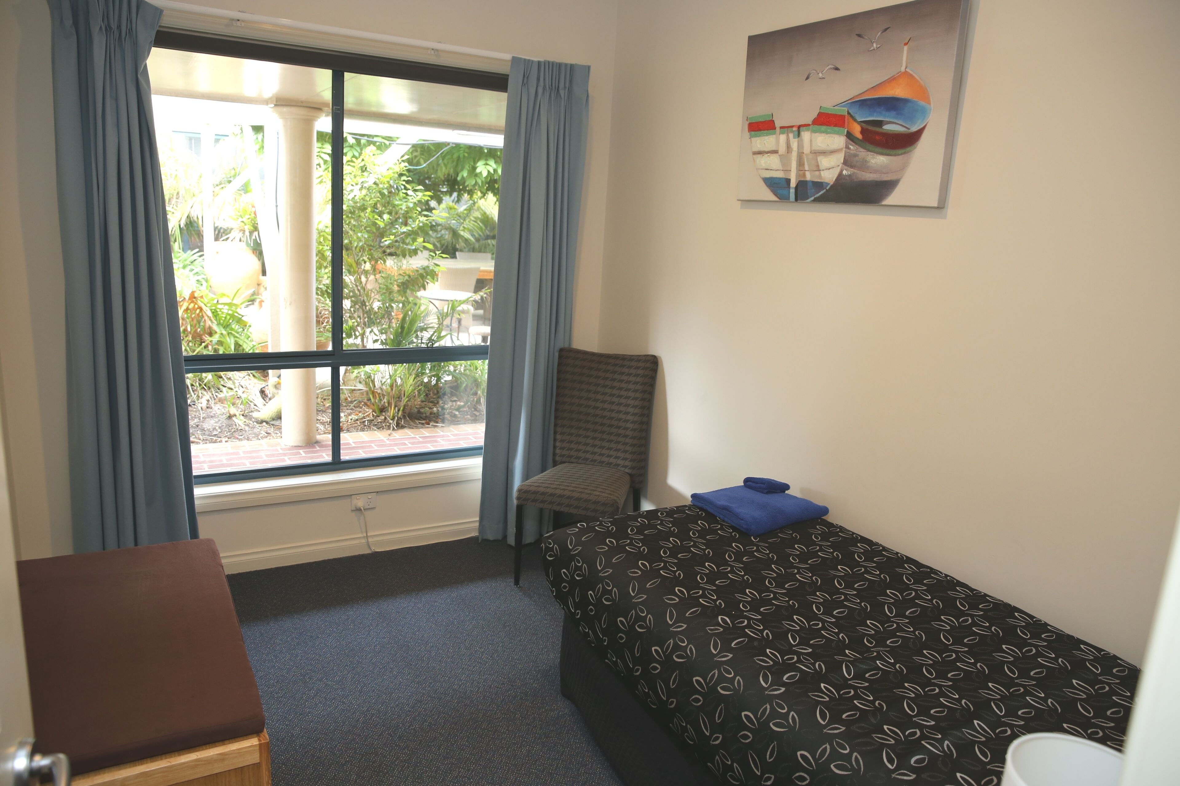 Een hotelkamer met een bed, een stoel, een bureau en een raam met gordijnen.