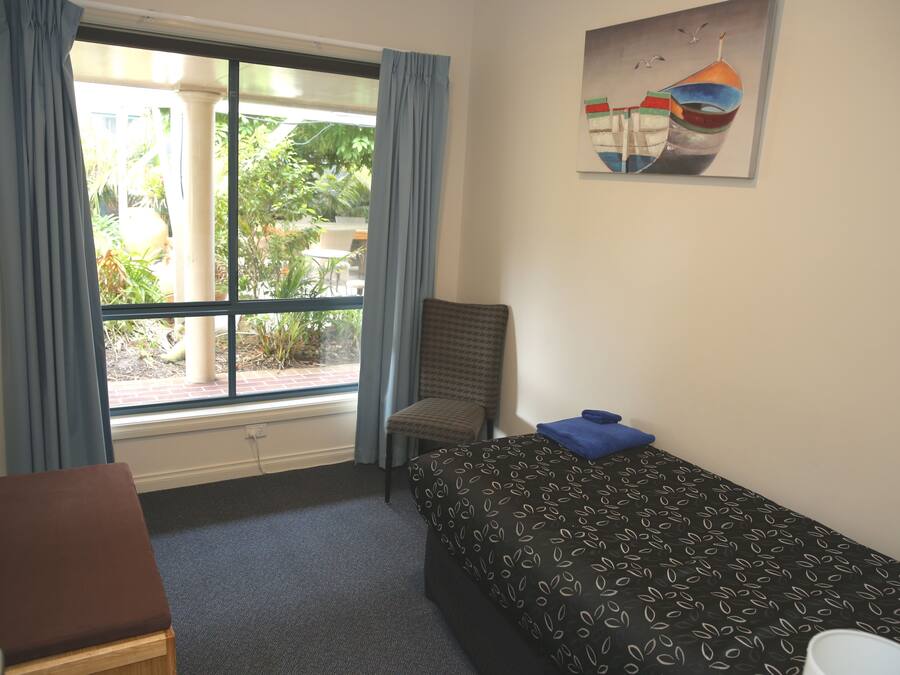 Een hotelkamer met een bed, een stoel, een bureau en een raam met gordijnen.