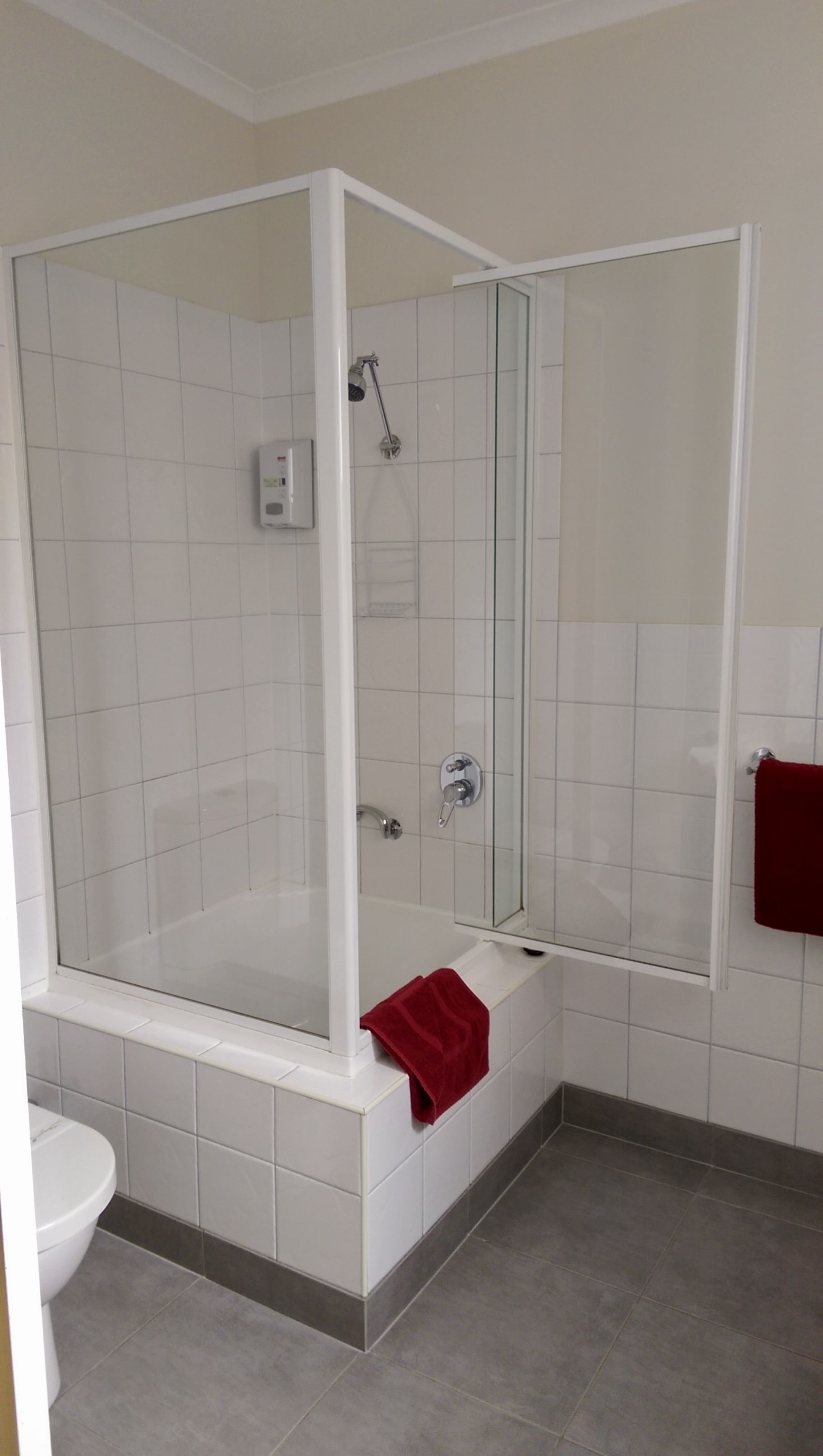 Un baño moderno con ducha de vidrio, bañera blanca y retrete.