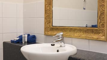 A bathroom with a white sink, a gold-framed mirror, and a black countertop.