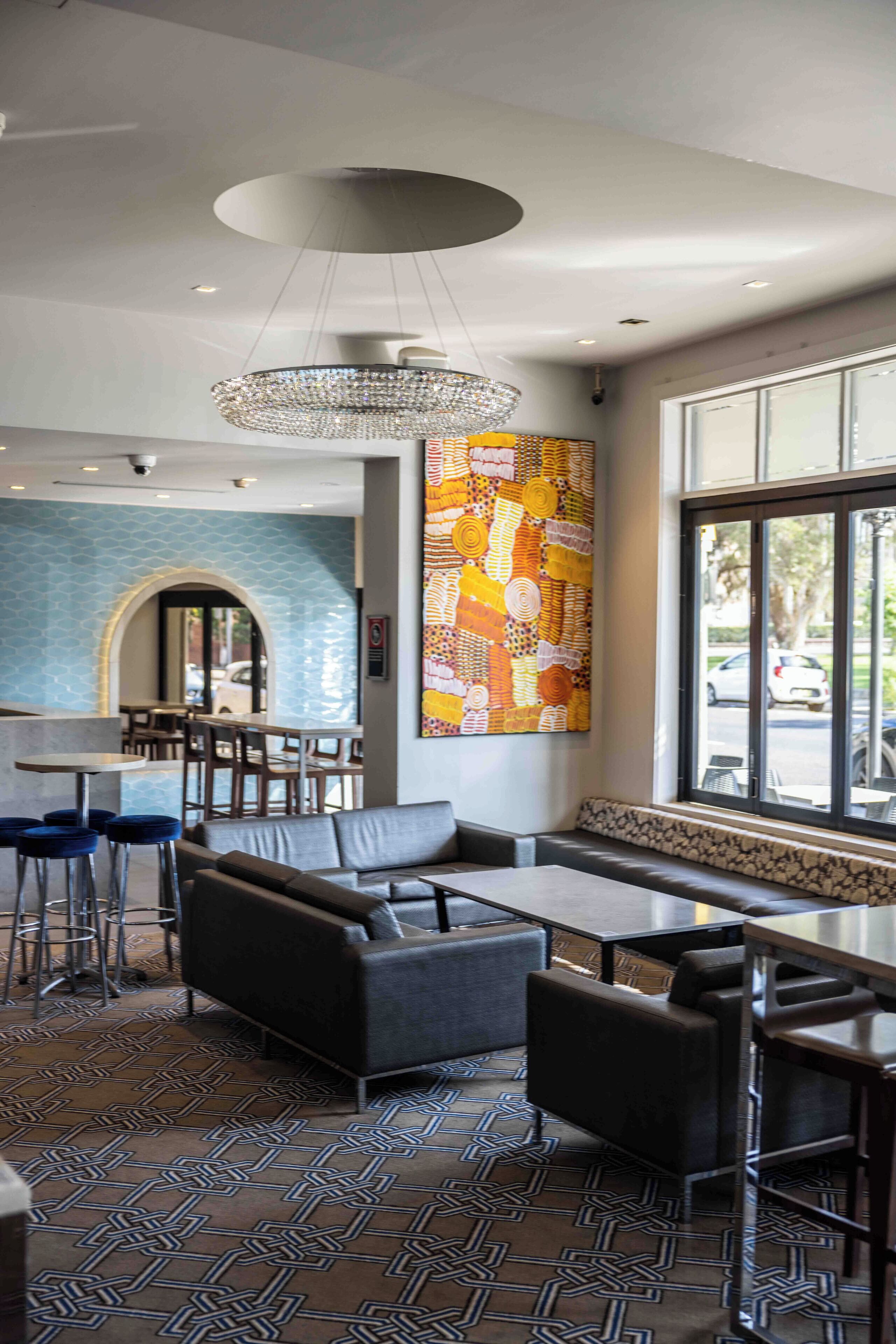 A modern interior with a seating area, a large window, and a decorative wall piece.