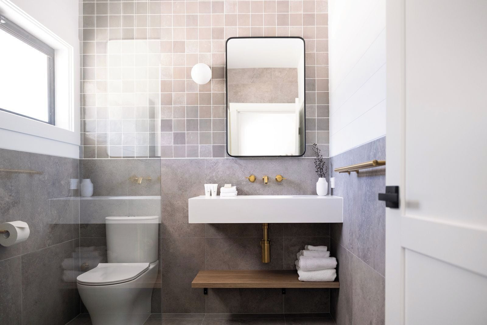 Et moderne badeværelse med toilet, vask og brusebad.