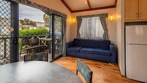A room with a dining table, blue sofa, and a refrigerator.