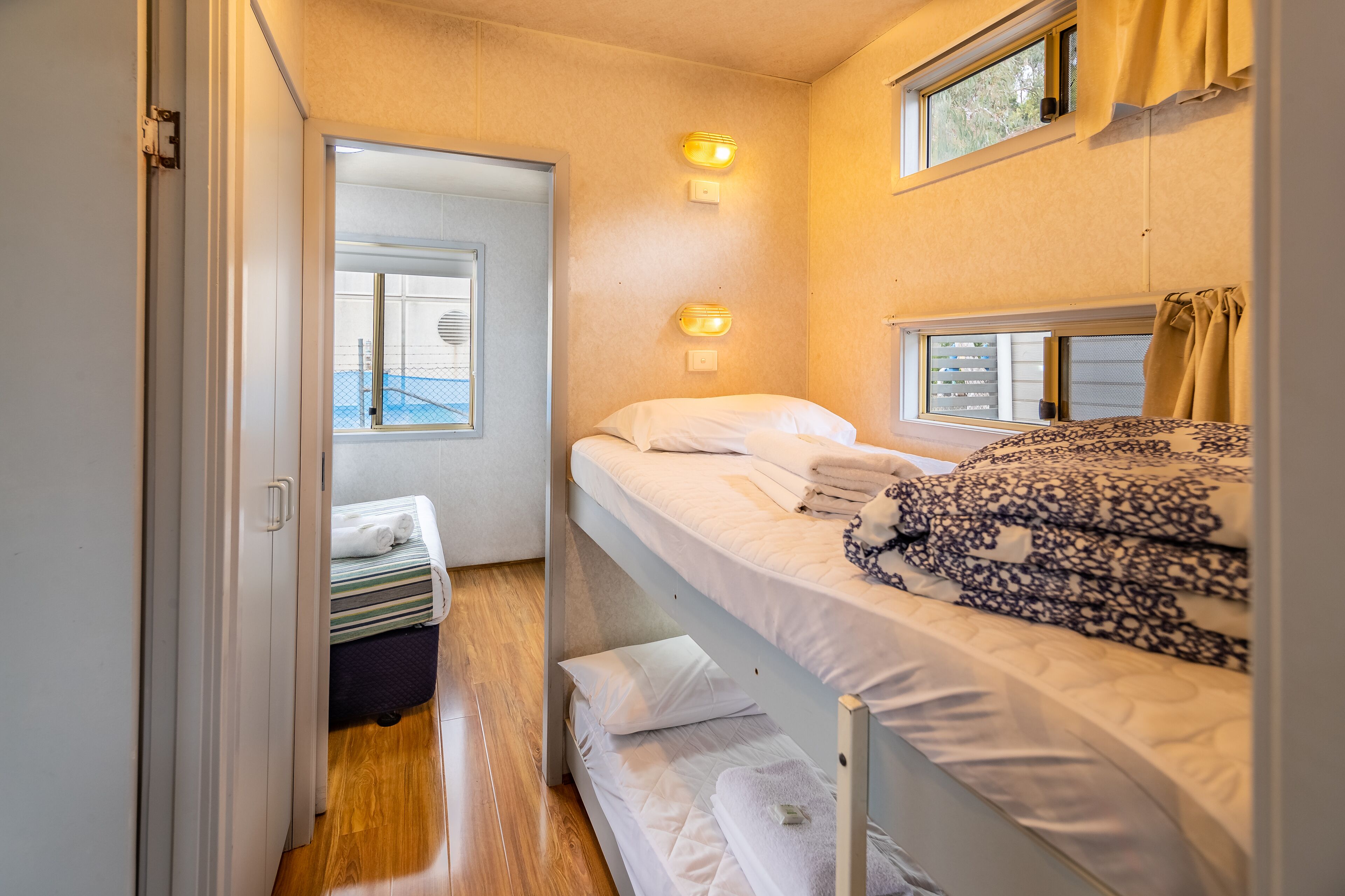 A compact room with bunk beds, a small window, and a door leading to another area.