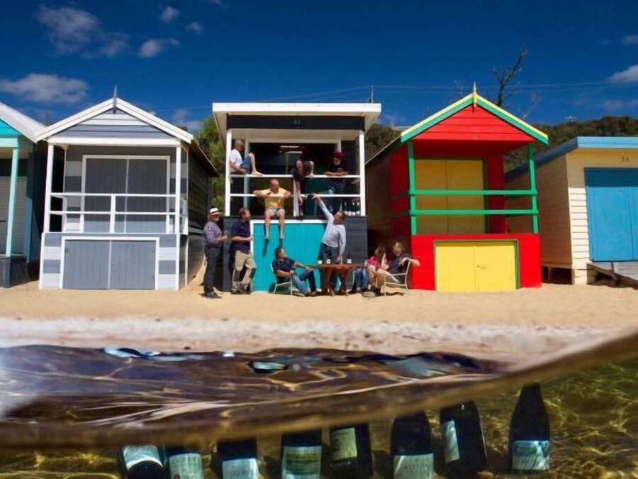 Un edificio frente a la playa con techo rojo, puerta azul y pared blanca.