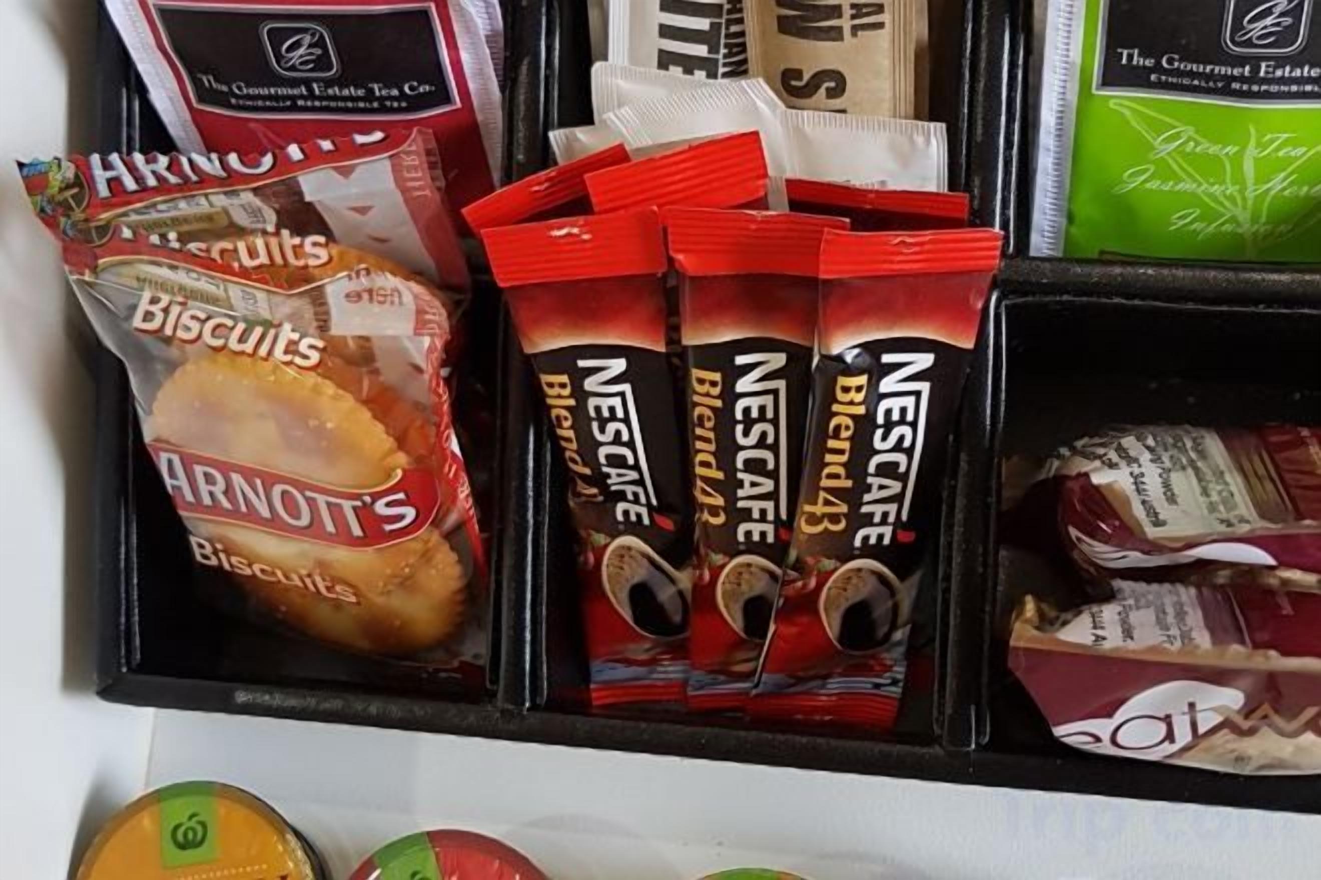 A shelf with various food items including biscuits and Nescafe blends.