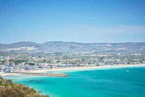 A coastal town with a beach, a pier, and a hilly background. - Bay Motel Safety Beach (Safety Beach)