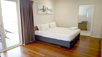 A bedroom with a large bed, a sliding glass door, and a bathroom visible through an adjacent door.