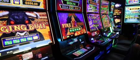 Una hilera de máquinas tragamonedas con diversos temas de juego y montos de premios mostrados.