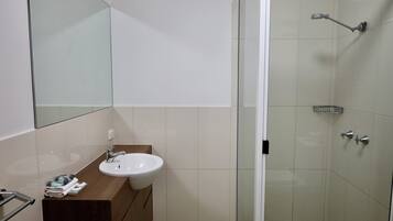 A bathroom with a sink, mirror, and shower.