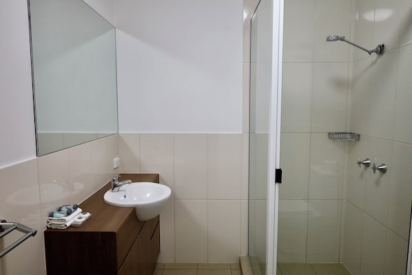 A bathroom with a sink, mirror, and shower. - The Australian Hotel Motel Dalby (Dalby)