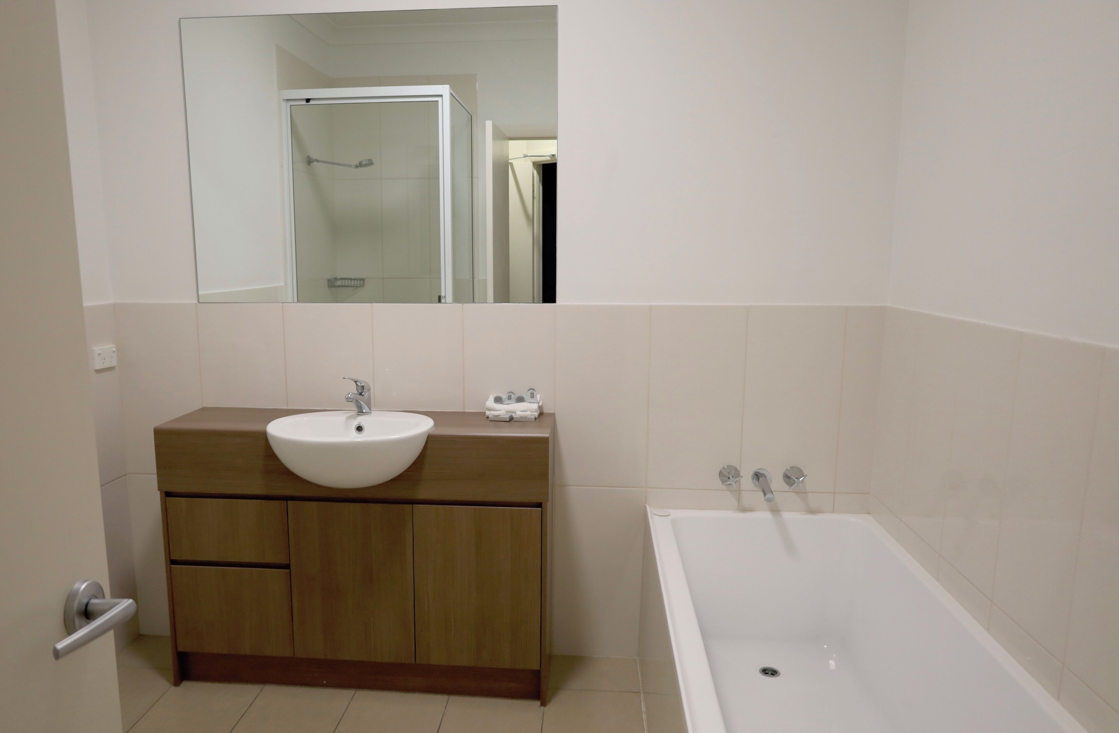 A bathroom with a wooden vanity, a white sink, and a bathtub.