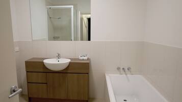 A bathroom with a wooden vanity, a white sink, and a bathtub.