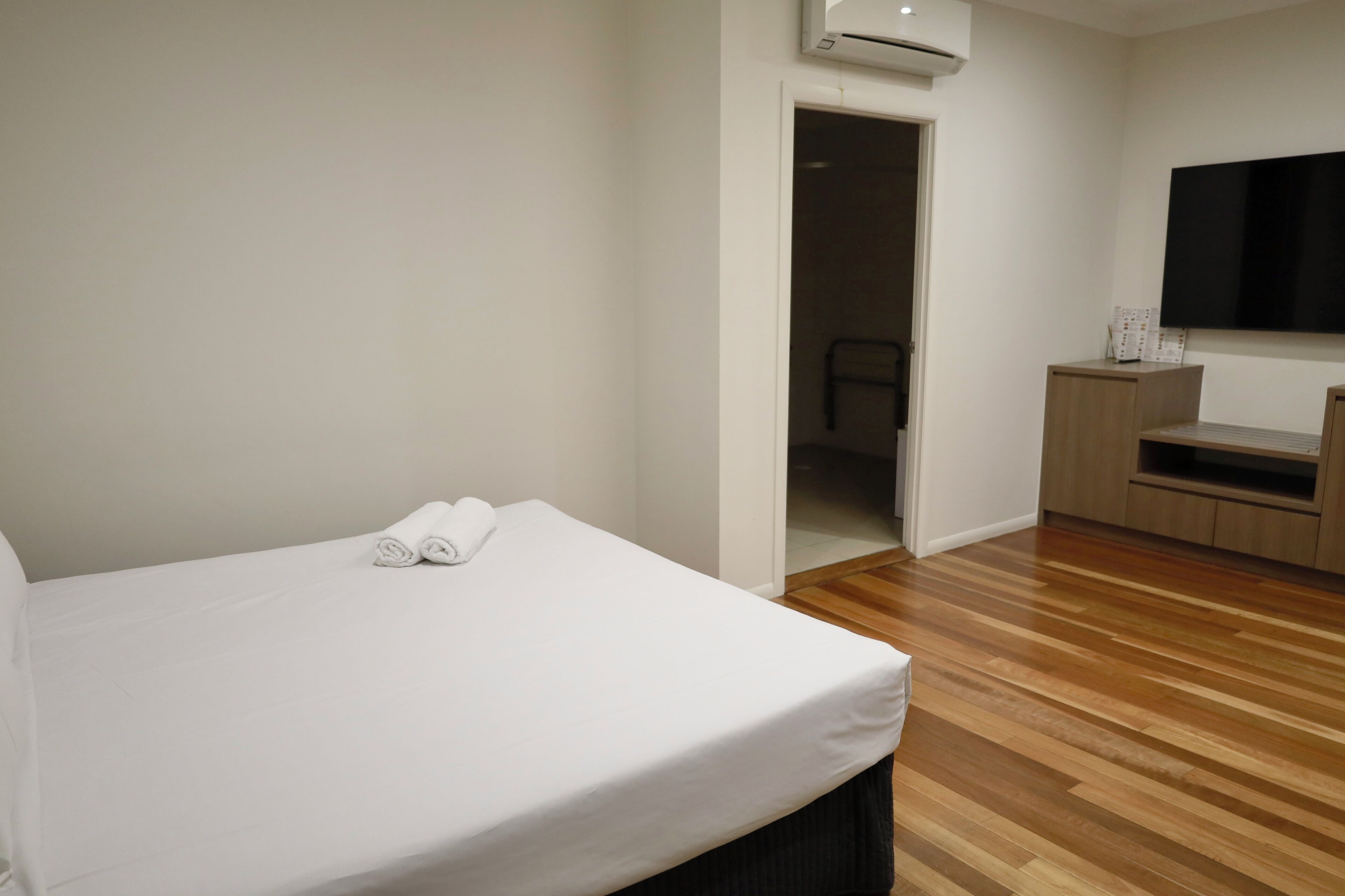 Habitación de hotel con cama, televisión de pantalla plana, piso de madera y un escritorio pequeño con silla.