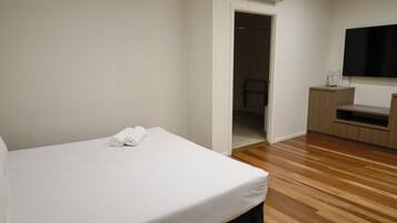 Habitación de hotel con cama, televisión de pantalla plana, piso de madera y un escritorio pequeño con silla.