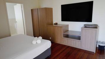 A bedroom with a bed, wooden wardrobe, TV, and a small table with a bowl.