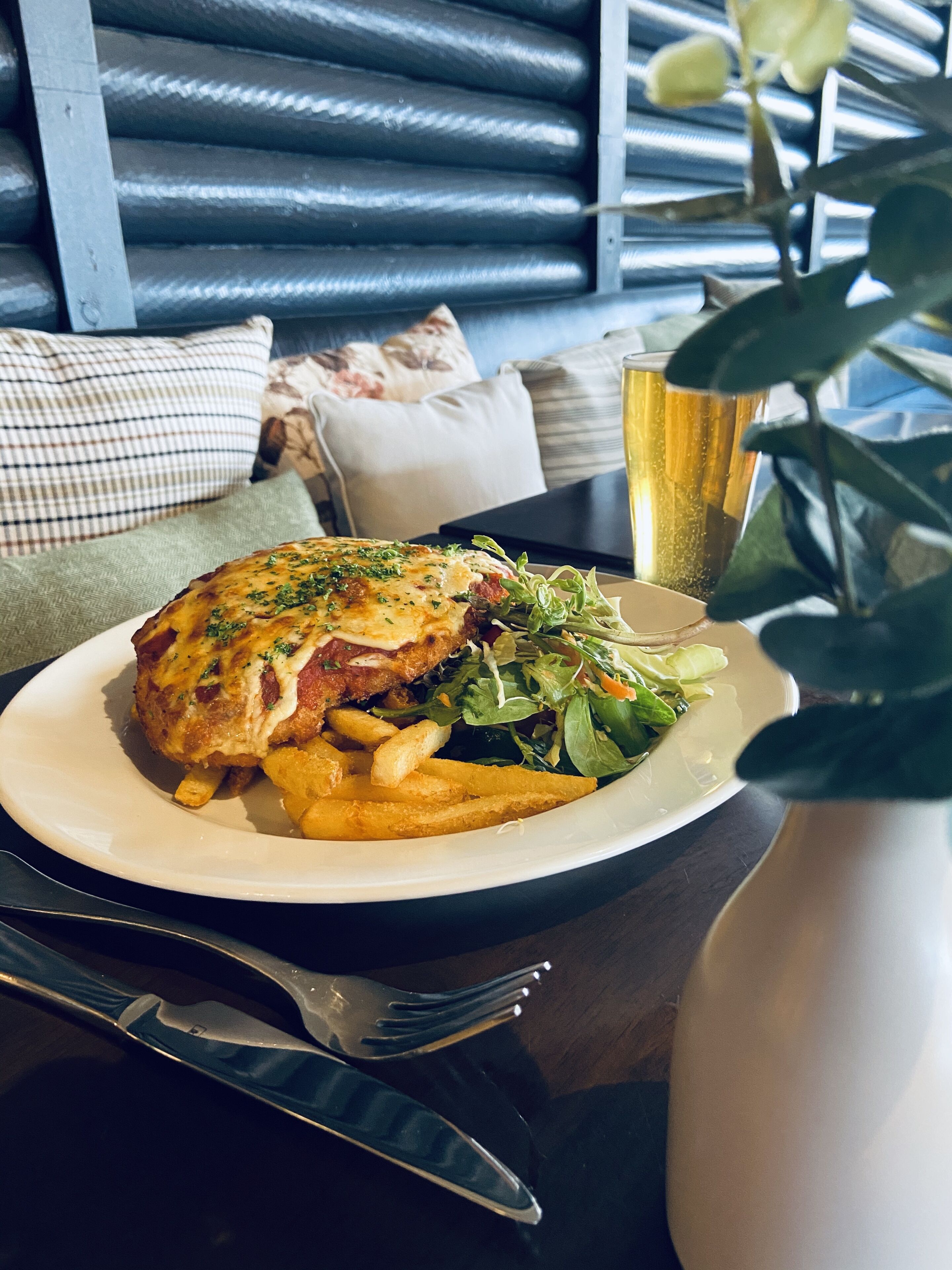 A plate of food with fries and a salad, a glass of drink, and a fork on a table.