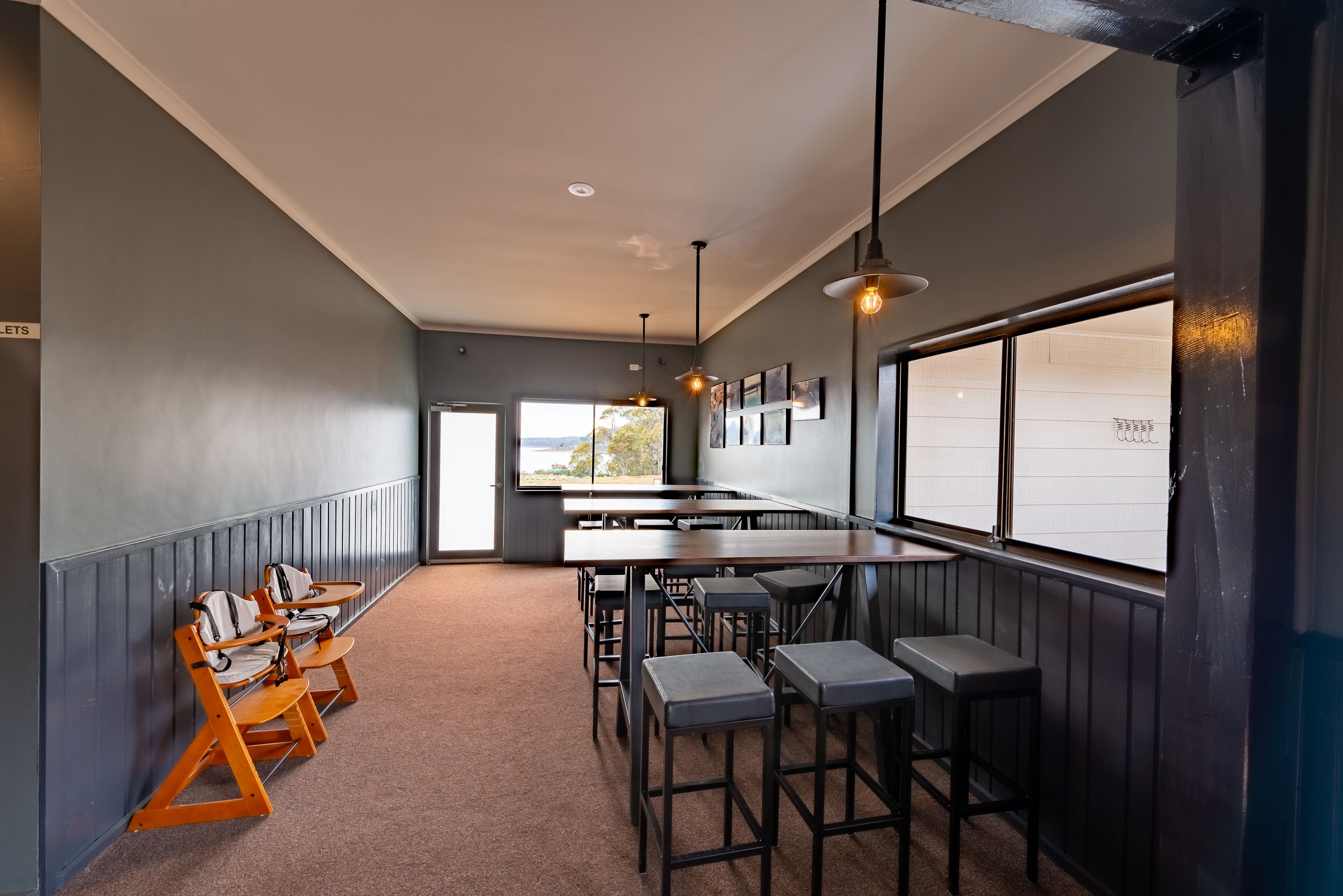 A modern interior with a long counter, bar stools, and a view through large windows.