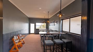A modern interior with a long counter, bar stools, and a view through large windows.