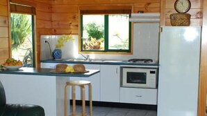 L’intérieur d’un chalet en bois comprend une cuisine, un coin repas et un canapé vert.