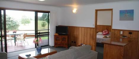 En stue med sofa, fjernsyn, et træskab og et spiseområde med bord og stole.