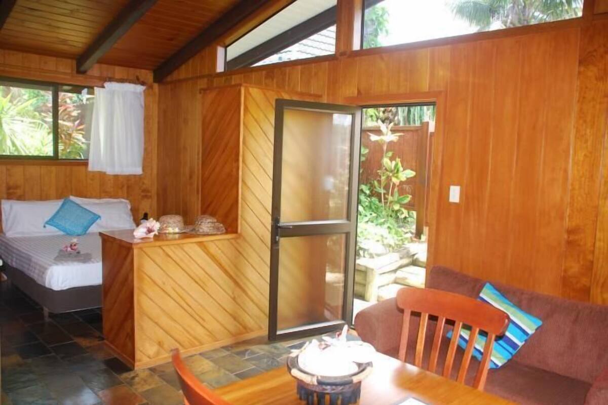 Quarto de madeira com uma cama, uma mesinha e um sofá.