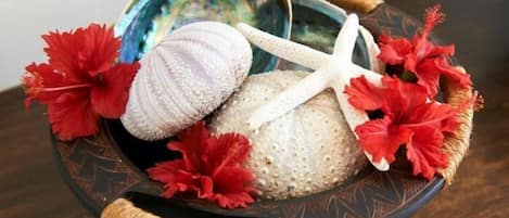 A decorative tray with shells, a starfish, and red flowers.