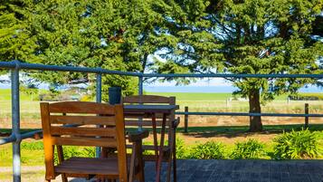 Sit and take in the serene views from this outdoor deck, surrounded by lush greenery and a distant horizon.
