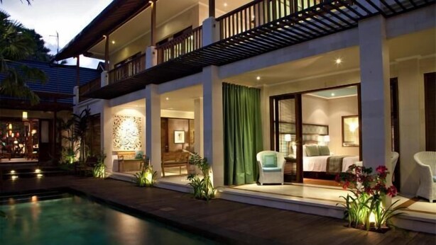 Un hotel con piscina, mobiliario exterior y un interior bien iluminado.