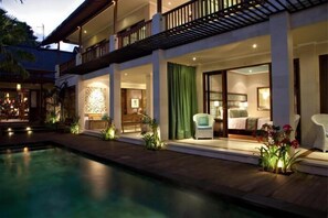 A hotel with a pool, outdoor seating, and a well-lit interior. - Cinta Grill & Inn (Ubud)