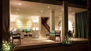 Una sala de estar moderna con una escalera, un conjunto de sofás y una pared decorativa.