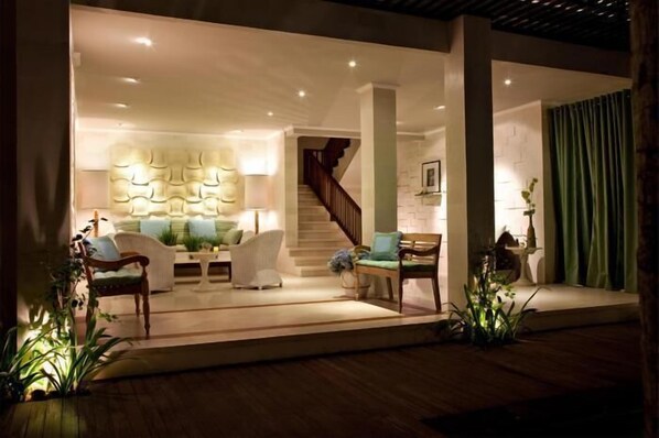 A modern living room with a staircase, a sofa set, and a decorative wall. - Cinta Grill & Inn (Ubud)
