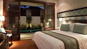 Un dormitorio con una cama grande, un escritorio con silla y un ventanal corredero que da a un espacio exterior con plantas.