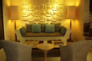 A cozy seating area with a sofa, two chairs, and a small table. - Cinta Grill & Inn (Ubud)