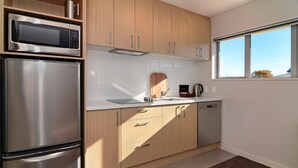 A modern kitchen with stainless steel appliances, wooden cabinets, and a window providing natural light. - Lincoln Motel (Lincoln)