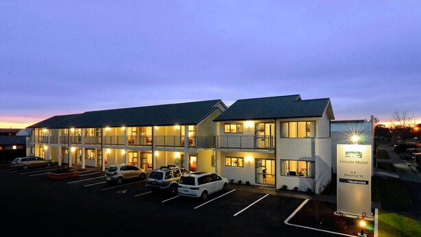 A motel with multiple floors, a parking lot with several cars, and a sign indicating it is the Lincoln Motel on Maurice St. - Lincoln Motel (Lincoln)