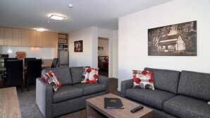 A modern living room with two grey sofas, a coffee table, and a kitchen area in the background. - Lincoln Motel (Lincoln)