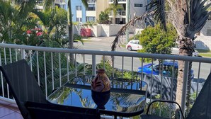 Un balcon avec deux chaises, une table en verre et un vase décoratif.