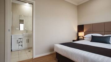 A hotel room with a bed, bedside table, lamp, and a bathroom with a mirror and sink.