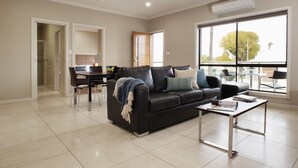 Una sala de estar moderna con un sofá de cuero negro, una mesa de centro y un comedor con una mesa y sillas.