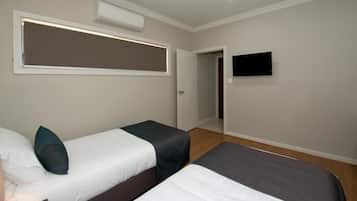 A hotel room with two beds, a flat-screen TV mounted on the wall, and an air conditioning unit above the beds.